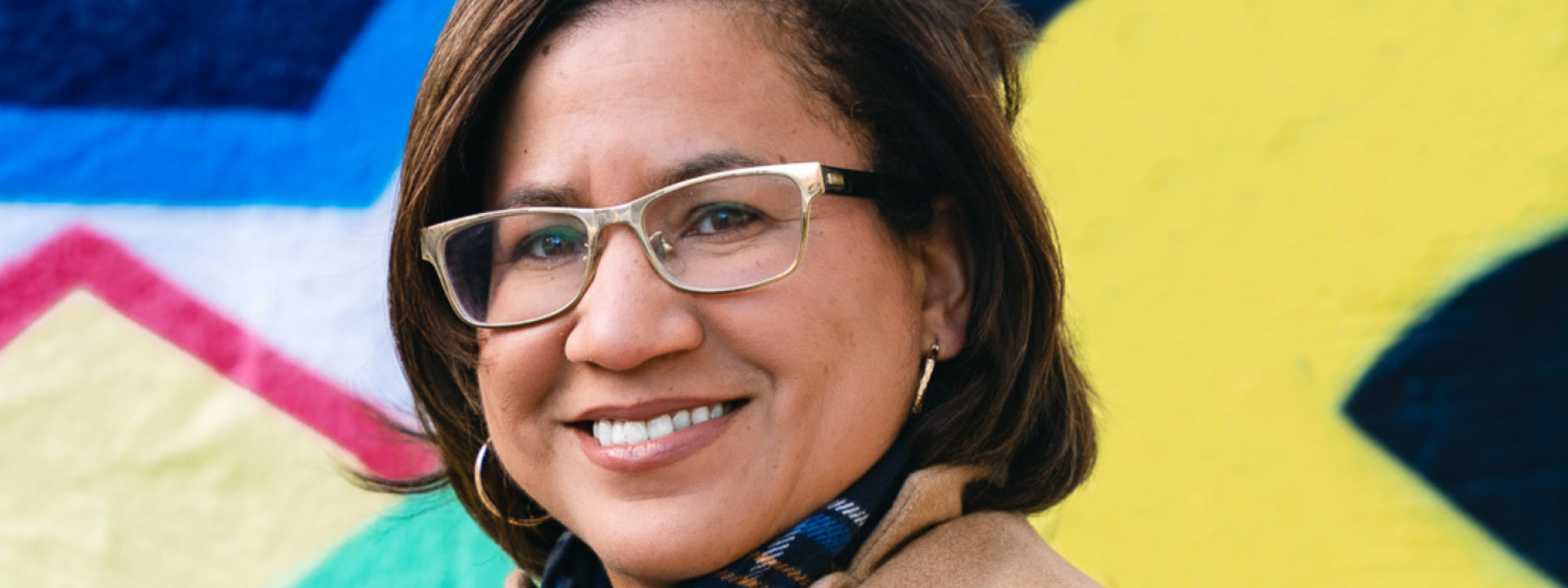 photo of a smiling women in front of a mural