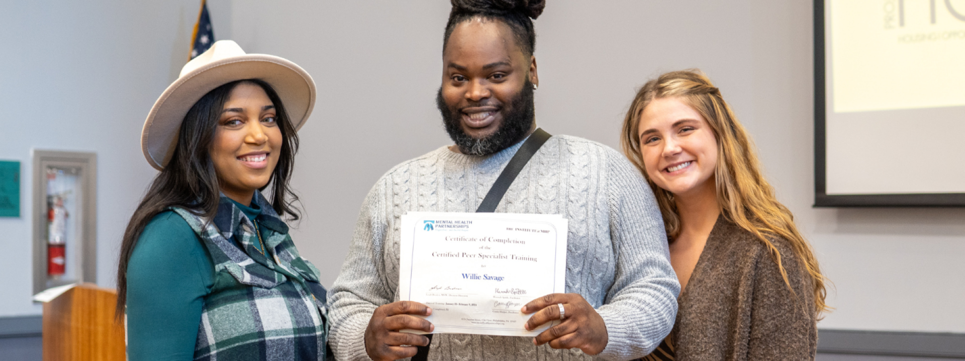 Three people standing with one holding a certificate