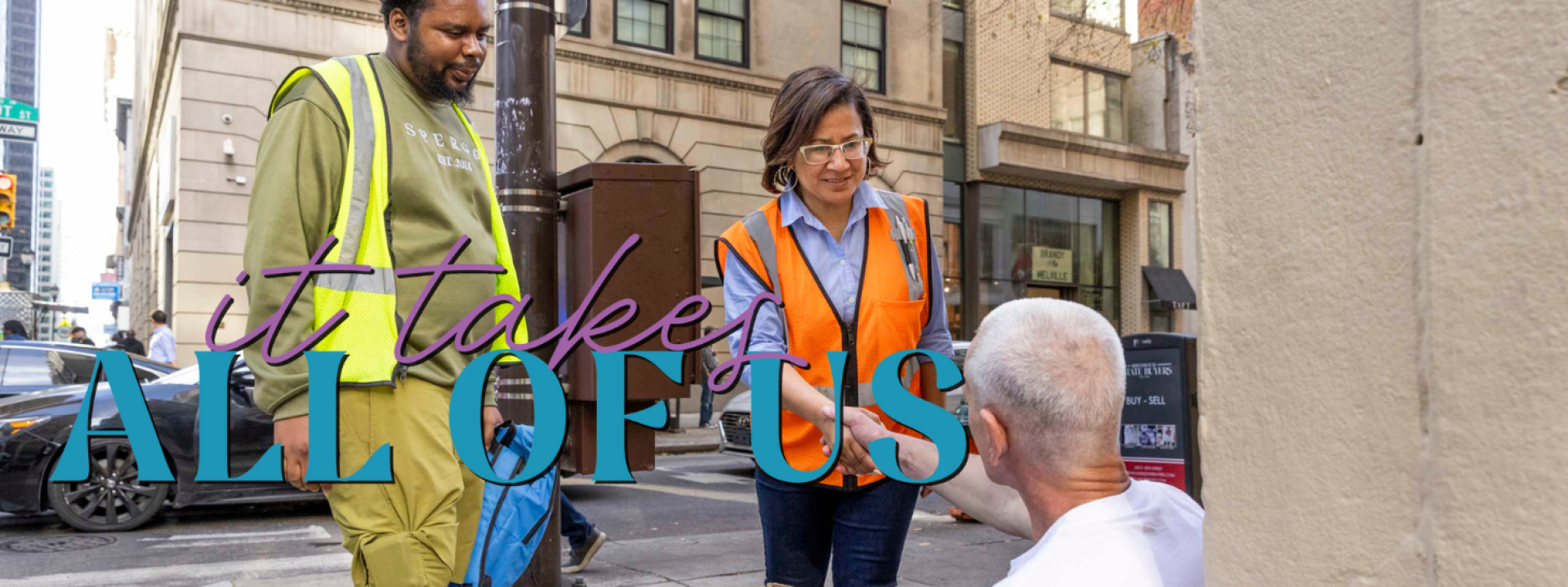 Two people standing and one person sitting.