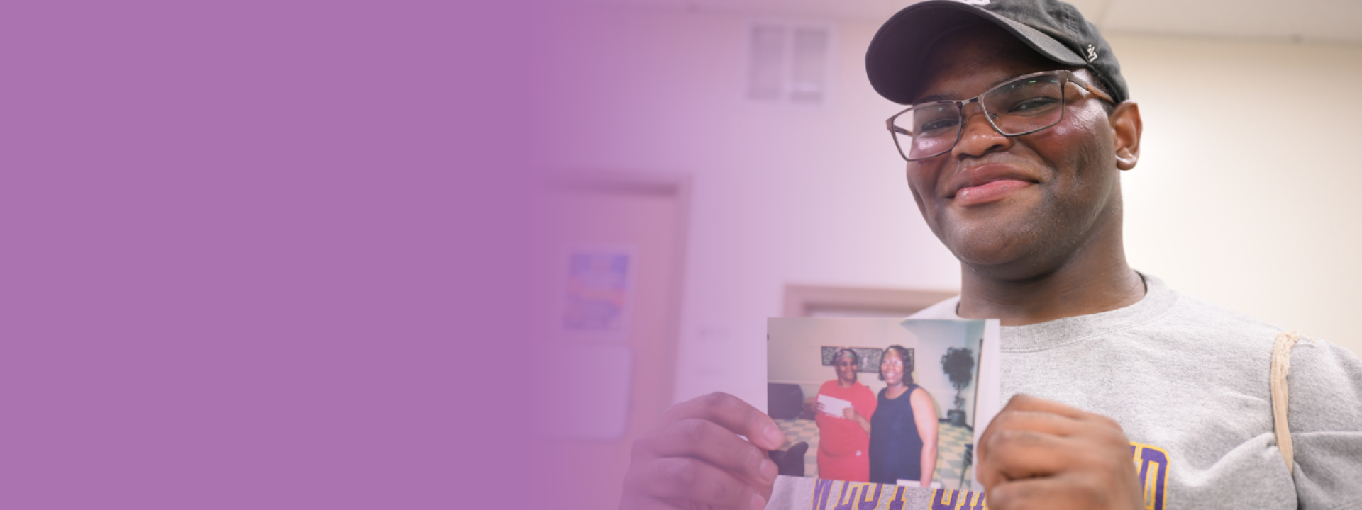 A smiling man holding an image of family members.