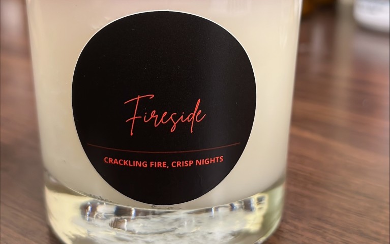 A candle labeled Fireside on a table.