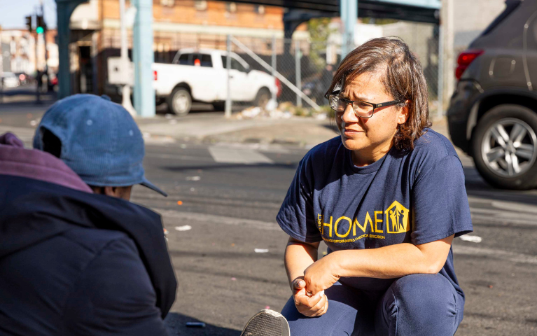 A woman crouching to speak with a person