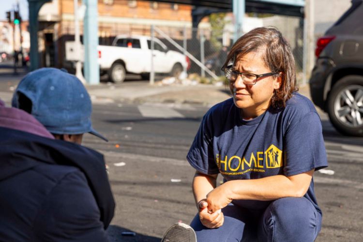 A woman crouching to speak with a person