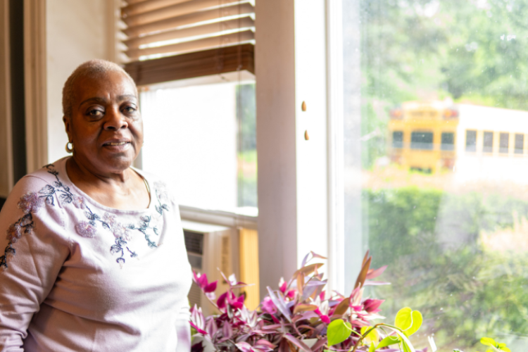 A woman standing by a sunny window.